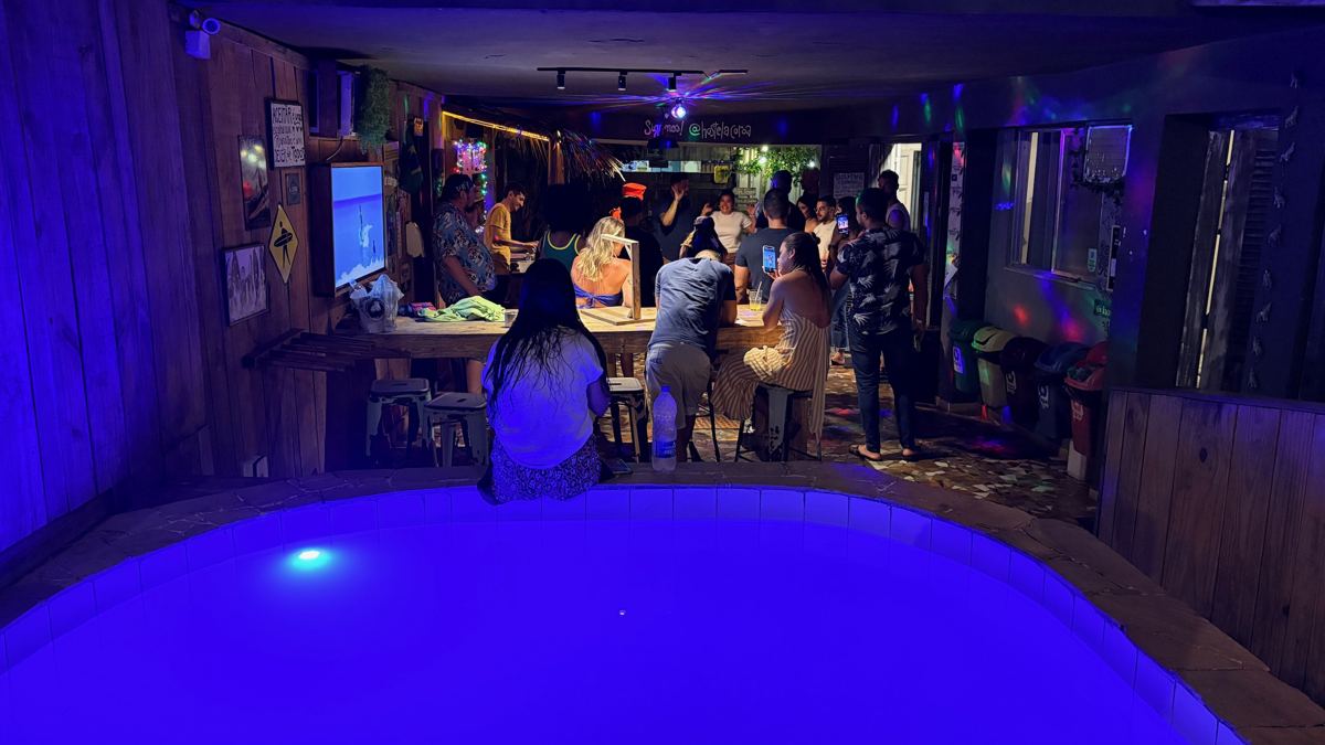 Piscina iluminada com o bar ao fundo à noite