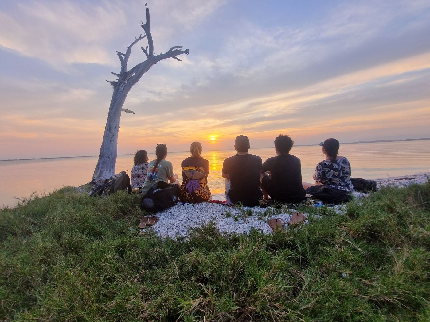 Hóspedes assistindo ao pôr do sol à beira da lagoa